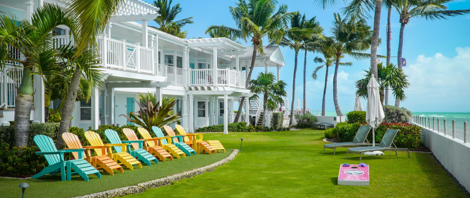 A vibrant lawn adorned with colorful lawn chairs and palm trees, creating a serene and inviting atmosphere.; Southernmost Beach Resort lawn, facing Kew West beach